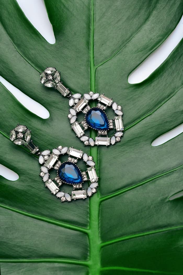 pair of silver-colored earrings with blue gemstone